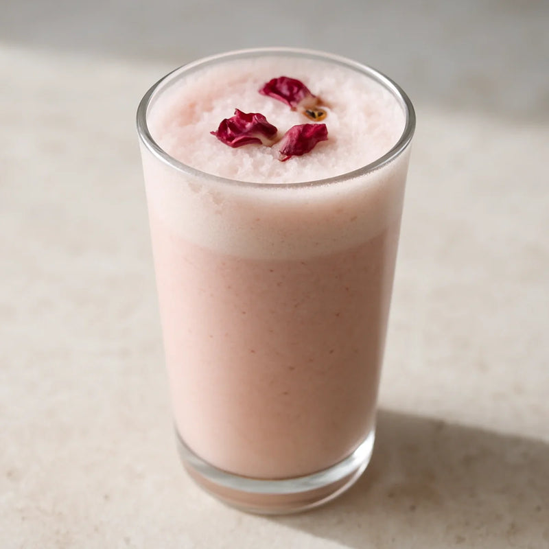 Pale blush-pink gulkand paan smoothie in a tall glass with rose petal garnish and light froth