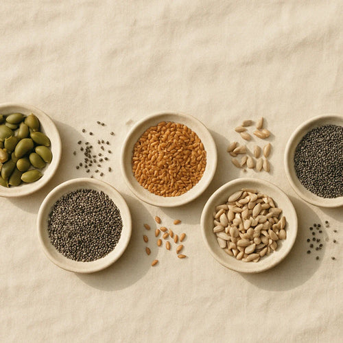 Five superfood seeds in ceramic dishes - pumpkin, chia, flax, sunflower, and basil seeds