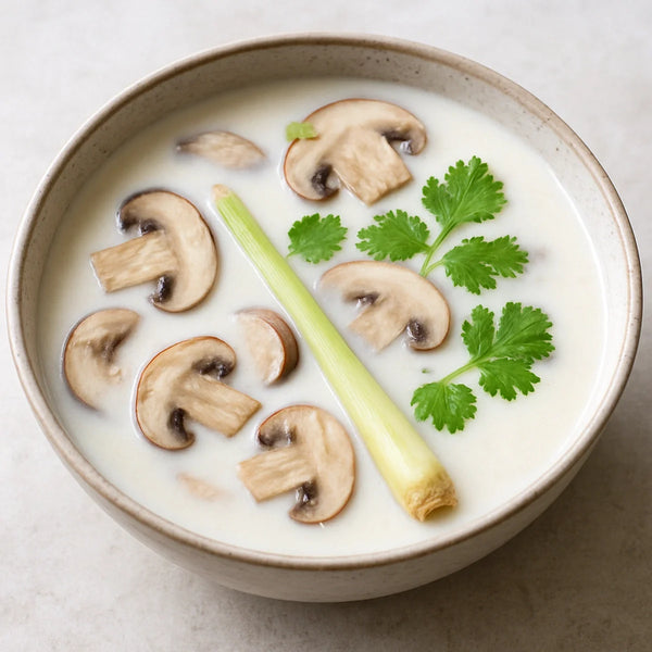 Creamy white Thai coconut soup in a wide ceramic bowl with mushrooms, lemongrass and fresh coriander