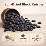 Sun-dried black raisins in wooden bowl with benefits: naturally processed, seedless, and rich source of fibre