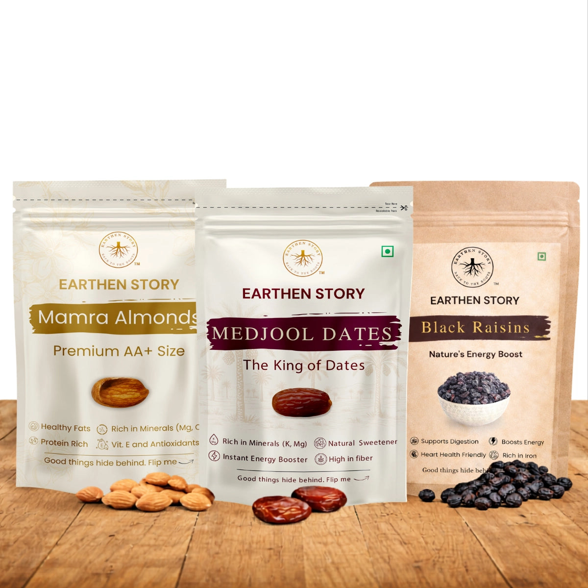 Dry Fruits Essentials Bundle with mamra almonds, medjool dates, and black raisins on a plain white background on a wooden desk.