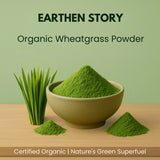 Earthen Story Organic Wheatgrass Powder in ceramic bowl with fresh wheatgrass sprouts and powder piles on wooden surface